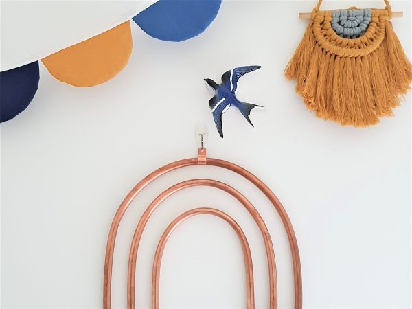 Copper rainbow hanging on the wall with navy and mustard decor