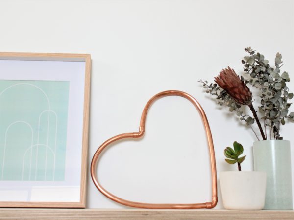 Copper heart sitting on a shelf with mint green decor
