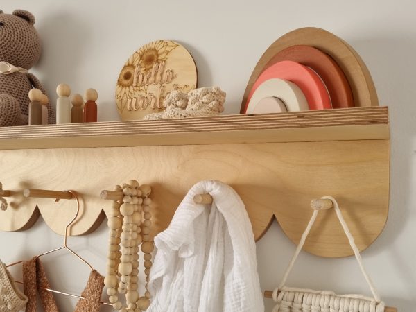 Close up of scalloped peg shelf with crochet booties and wooden rainbow decor